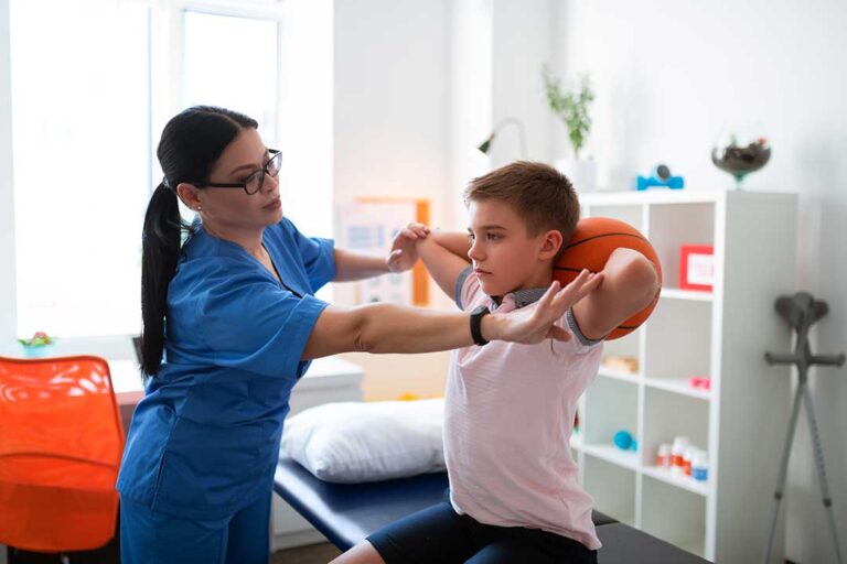 An older adult doing gentle hand exercises with a physical therapist in a bright, home-like therapy room.